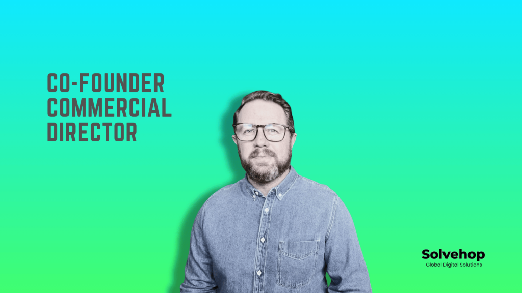 Friendly and professional image of Graeme Wattie, co-founder and commercial director at solvehop. Denim shirt, glasses, beard, blue green background